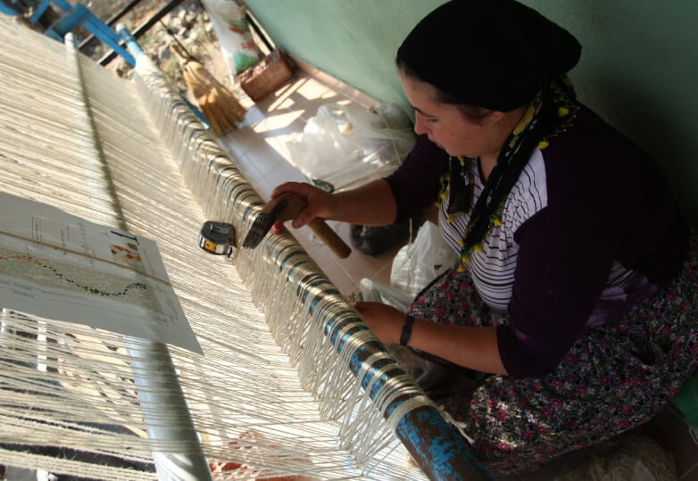 まだ染められてない糸を紡ぐ女性の写真