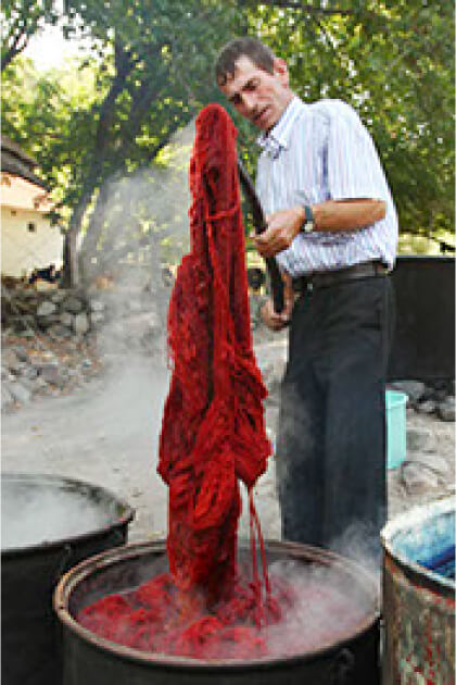 天然染料で糸を染め上げる織り手の男性の写真